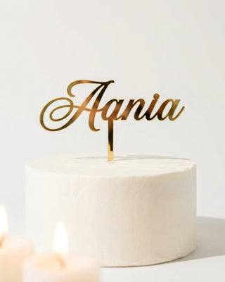 Personalized gold acrylic name cake topper on a white celebration cake